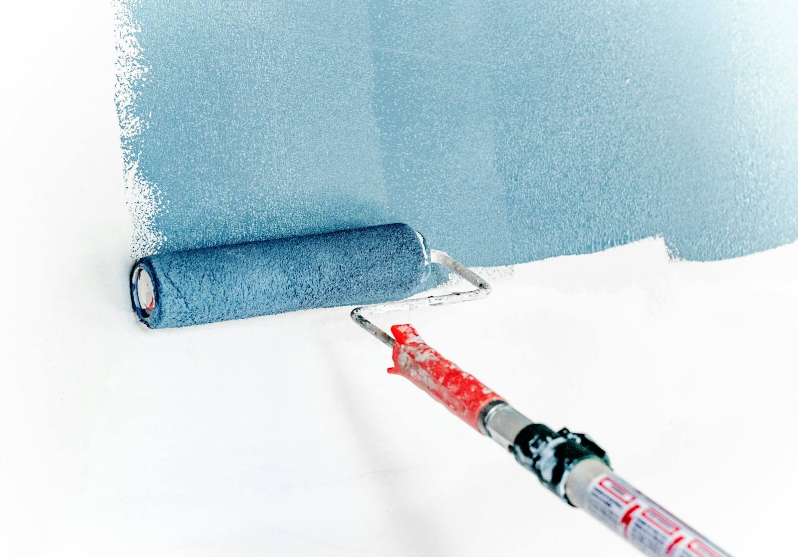 Farbroller mit blauer Farbe an einer weißen Wand